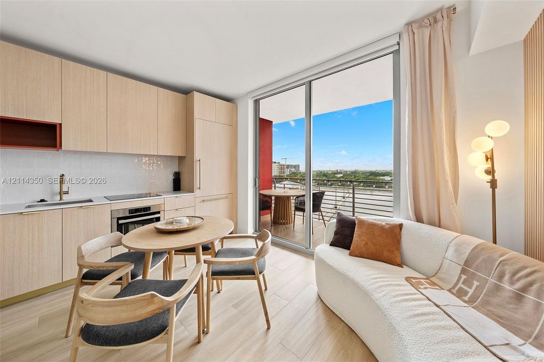 Kitchen featuring light wood-finish cabinetry, integrated appliances, and a glass sliding door leading to a balcony