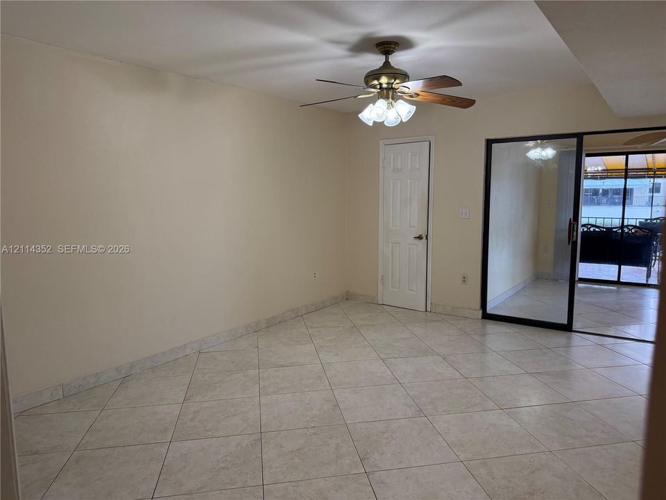 Ceramic tile flooring set on a diagonal, ceiling fan with multi-light fixture, and sliding glass patio door