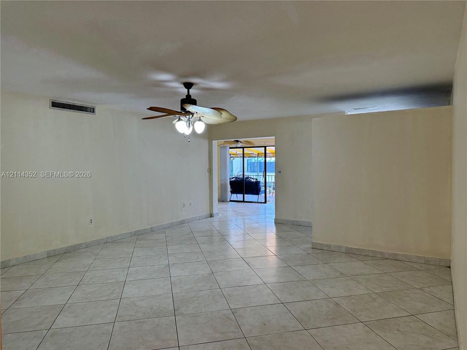 Large format tile flooring throughout, ceiling fan with integrated lighting, and glass sliding doors
