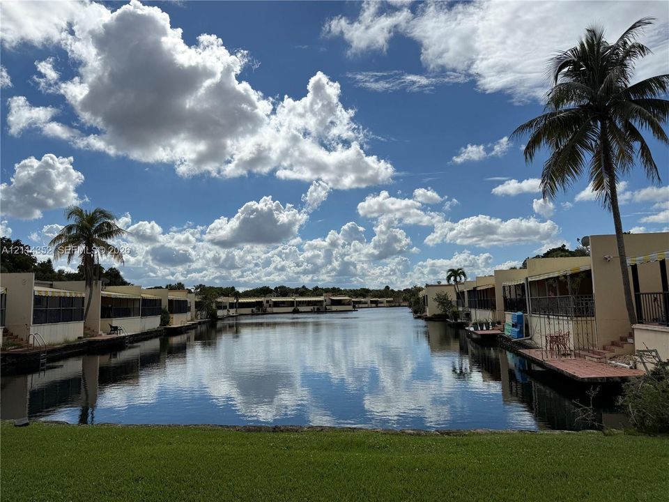 Waterfront setting featuring a canal-front bulkhead, private dock access, and mature palm trees
