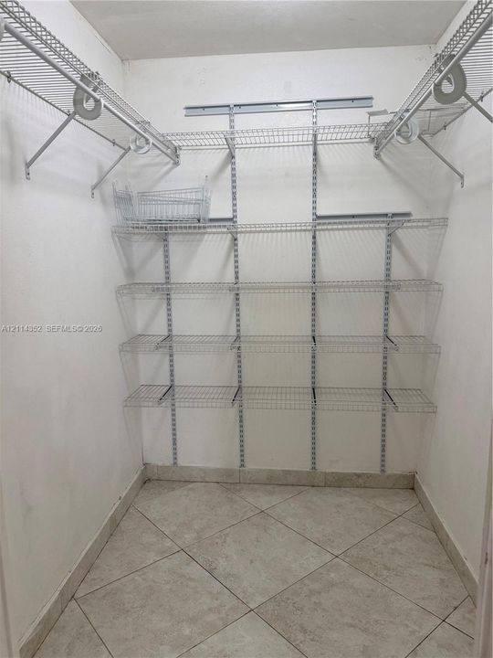 Walk-in closet featuring floor-to-ceiling adjustable wire shelving, multi-level hanging rods, and large-format tile flooring