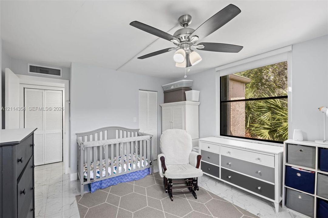 Room featuring large-format tile flooring, a multi-blade ceiling fan with integrated lighting, and louvered closet doors