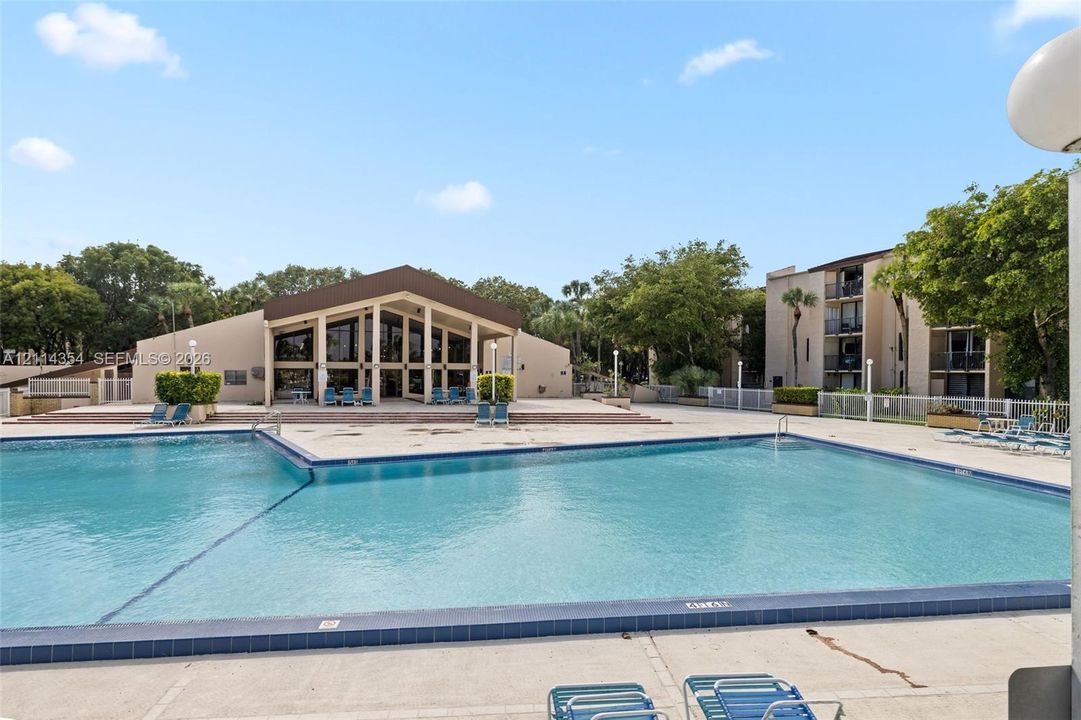 Swimming pool with tiled coping, surrounding concrete deck, and multi-story building exterior