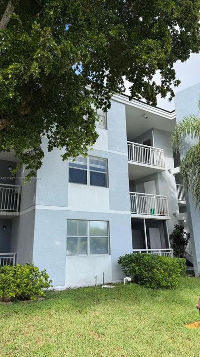 Multi-level exterior featuring light-toned stucco siding, private balconies with metal railings, and a screened-in ground-floor porch