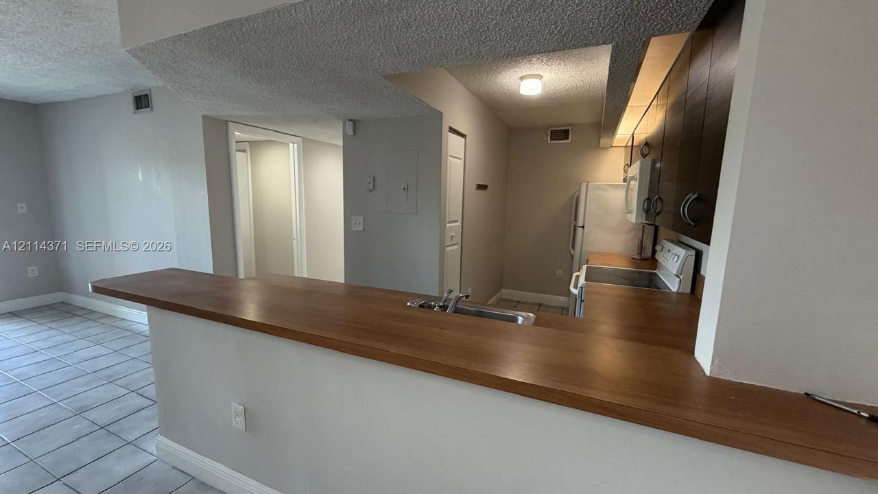 Kitchen featuring a wood-surface breakfast bar, dark-finish cabinetry, tile flooring, and overhead flush-mount lighting