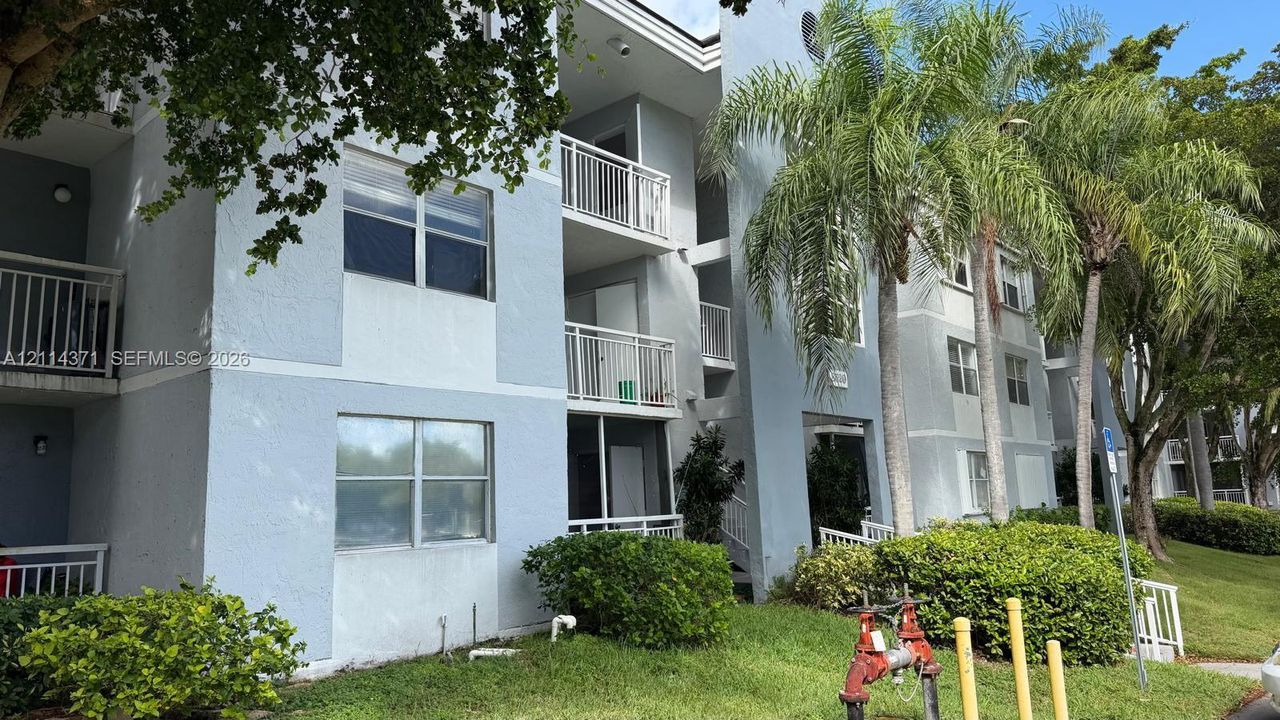Multi-story exterior featuring light-toned stucco siding, private screened-in balconies with metal railings, and integrated multi-pane windows
