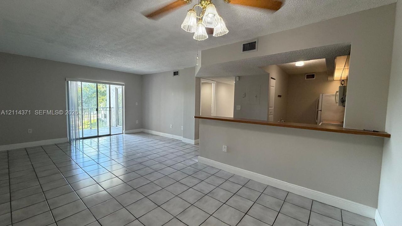 Neutral tile flooring, sliding glass doors, and a kitchen pass-through counter with a wood-finish topper