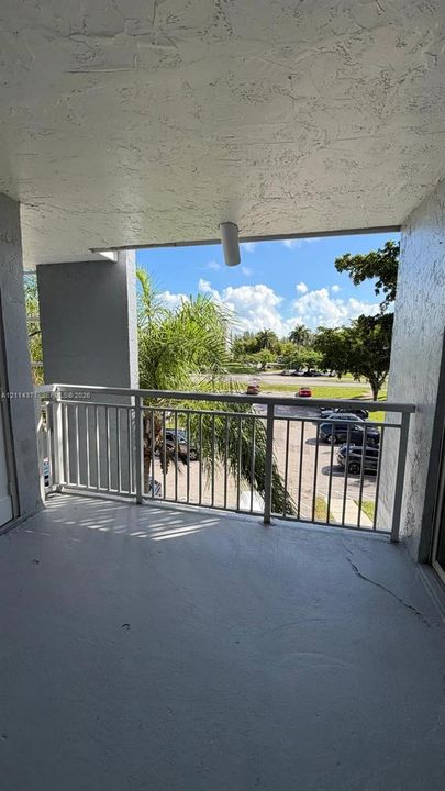 Covered balcony featuring concrete flooring, white metal railing, and a mounted ceiling light fixture