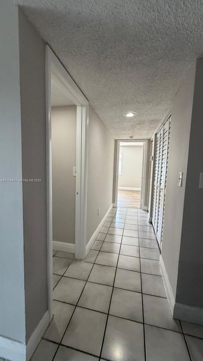 Ceramic tile flooring with neutral grout, recessed lighting, and white louvered bifold closet doors