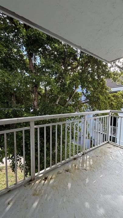 Covered balcony featuring white vertical railings and concrete flooring