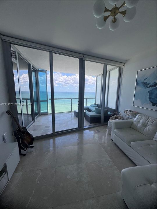 Floor-to-ceiling sliding glass doors, balcony with stone tile flooring, polished stone flooring, and multi-globe ceiling fixture