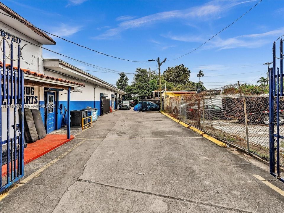 Paved exterior area featuring metal perimeter fencing, gated access, and concrete surfacing