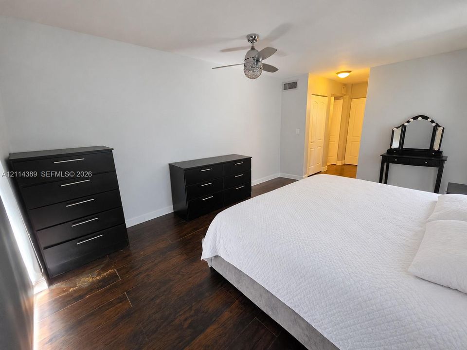 Wood-finish tile flooring, white porcelain toilet, and ceiling-mounted flush light fixture