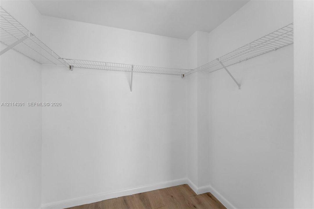 Walk-in closet featuring white walls, wood-finish flooring, and white wire shelving