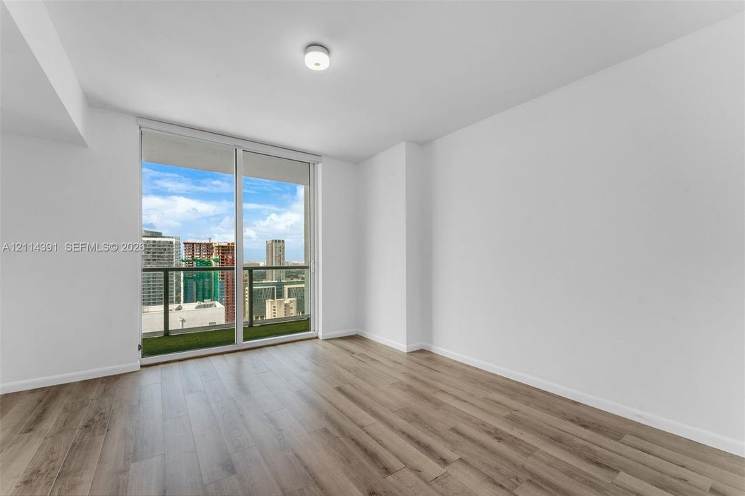 Floor-to-ceiling windows, private balcony access, wood-finish flooring, and recessed ceiling lighting