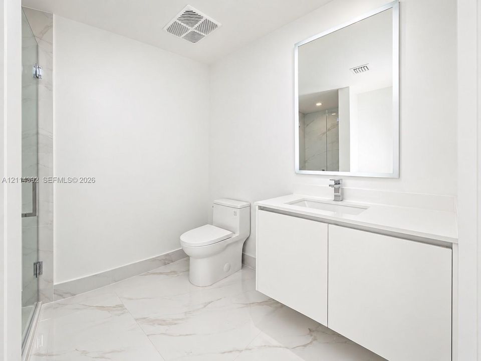 Modern bathroom featuring a floating vanity with a seamless countertop, rectangular sink, polished-edge mirror, and floor-to-ceiling tiled shower with a frameless glass door