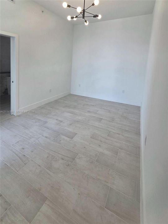 Room interior featuring light-toned tile flooring, neutral walls, and a modern multi-arm light fixture
