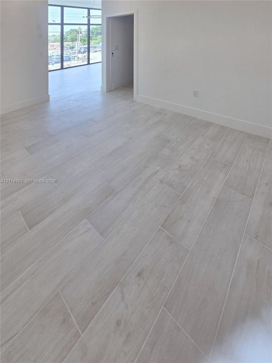 Interior space featuring wood-finish tile flooring, neutral wall tones, and floor-to-ceiling multi-pane glass panels