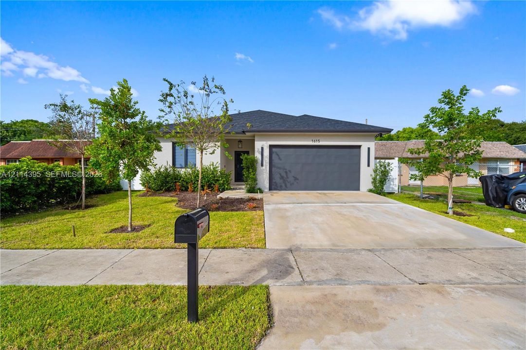 Single-story exterior featuring a hip roof, stucco facade, concrete driveway, two-car garage, and established landscaping