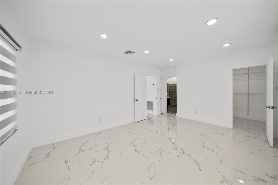 Neutral-toned flooring with veined detailing, recessed ceiling lighting, and built-in closet storage