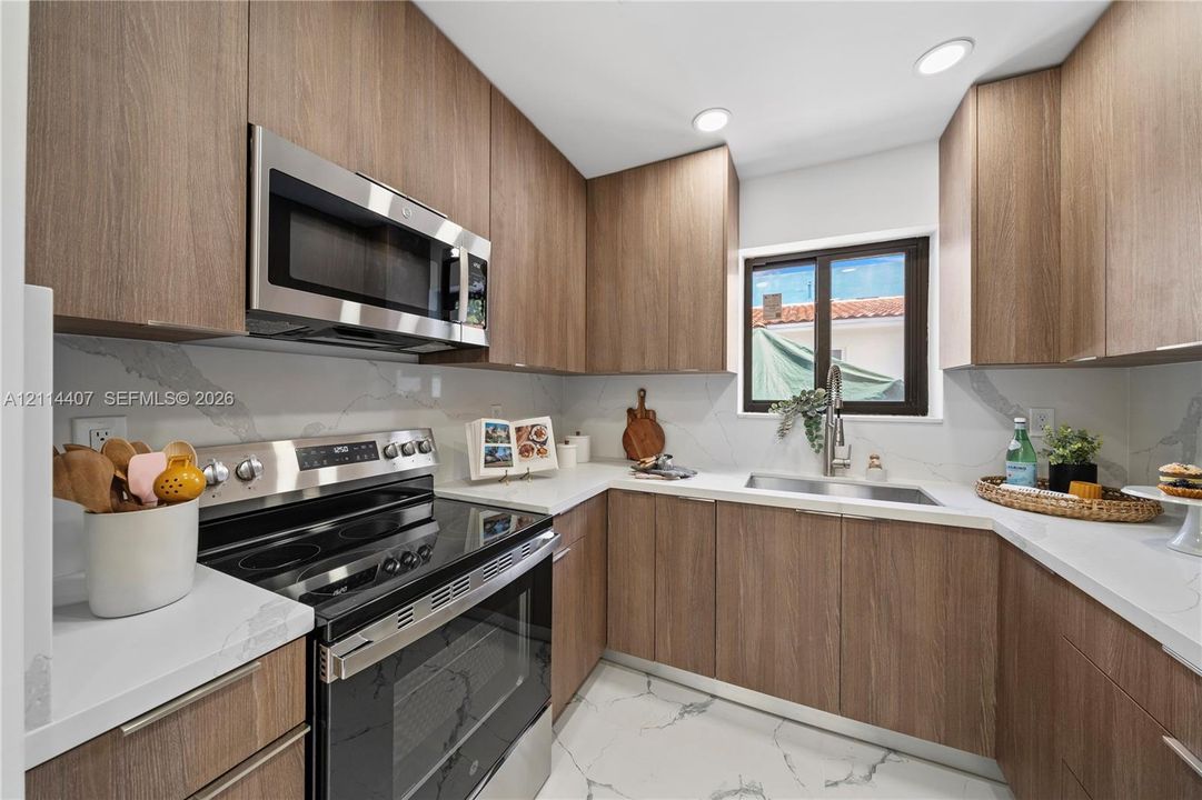 Kitchen featuring wood-finish cabinetry, stainless steel appliances, stone-patterned countertops, a full-height stone-patterned backsplash, and stone-patterned flooring