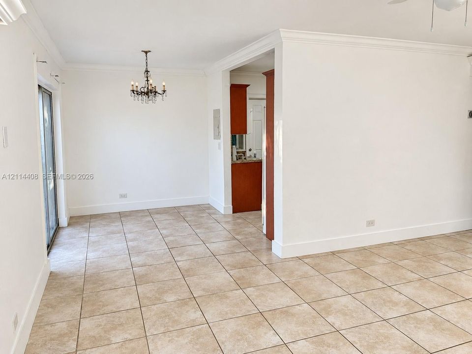 Ceramic tile flooring, crown molding, multi-arm chandelier, and sliding glass door