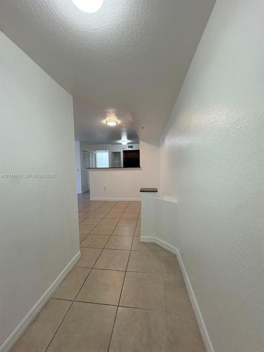 Neutral-toned ceramic tile flooring, low-profile partition wall with stone-capped ledge, and recessed ceiling lighting