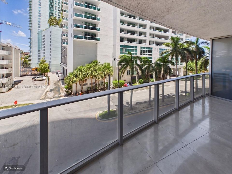 Covered balcony featuring large-format tile flooring and a glass-panel railing with metal frame
