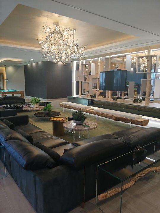 Recessed tray ceiling featuring a multi-light branching chandelier, bespoke built-in shelving with integrated lighting, and custom wood-slab bench seating