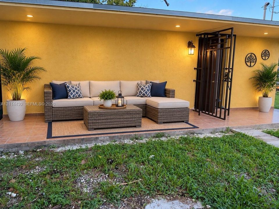 Covered outdoor patio featuring terra cotta tile flooring, recessed lighting, and a metal security screen door