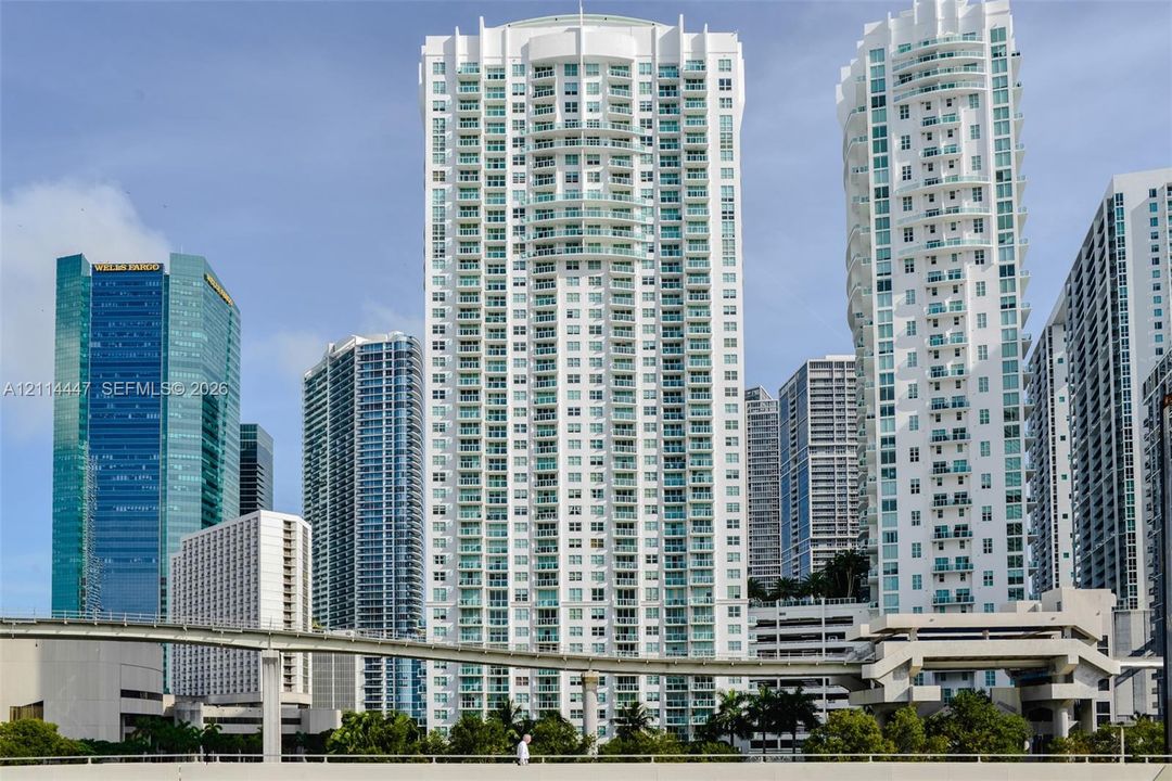 High-rise condominium tower featuring a white concrete facade, uniform glass balcony railings, and a symmetrical structural design