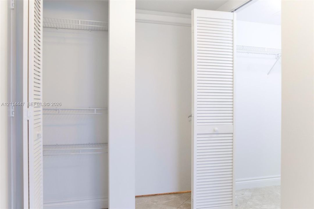 Closet featuring white louvered doors and multi-tier wire shelving
