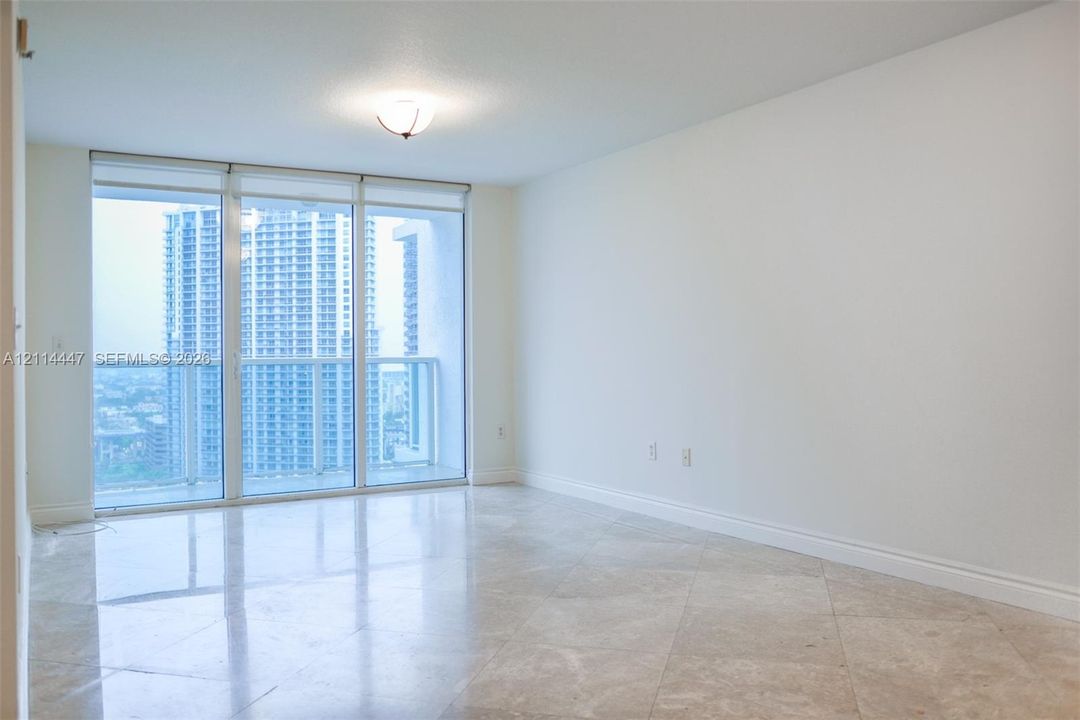 Open-concept room featuring polished stone flooring, floor-to-ceiling glass paneling, and an attached balcony with exterior railings