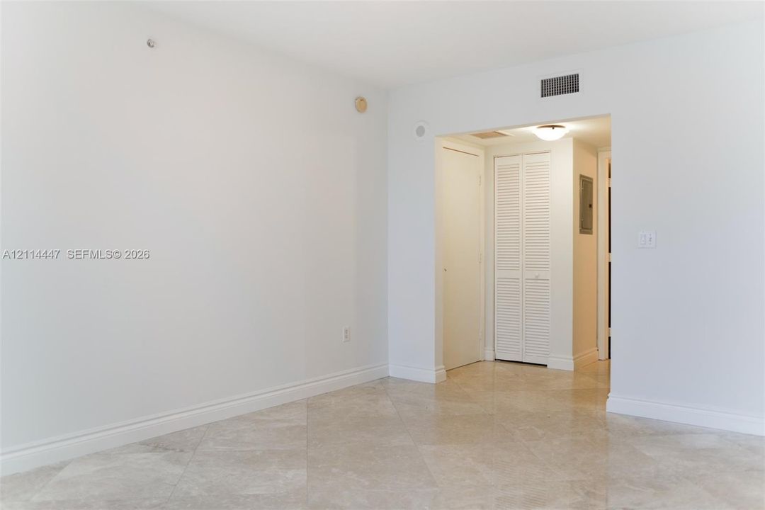 Neutral-toned stone flooring laid in a diamond pattern, featuring crisp white wall finishes and a white louvered-door closet