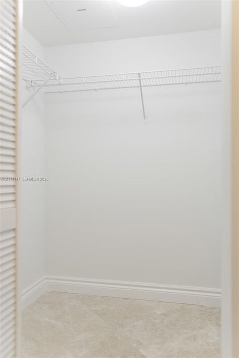 Storage area featuring white interior walls, white wire shelving, and neutral-toned tile flooring