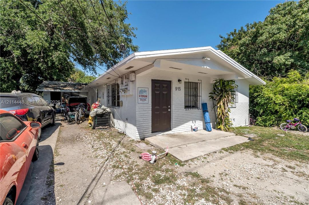 Single-story exterior featuring painted masonry siding, a concrete entry porch, and a dedicated driveway