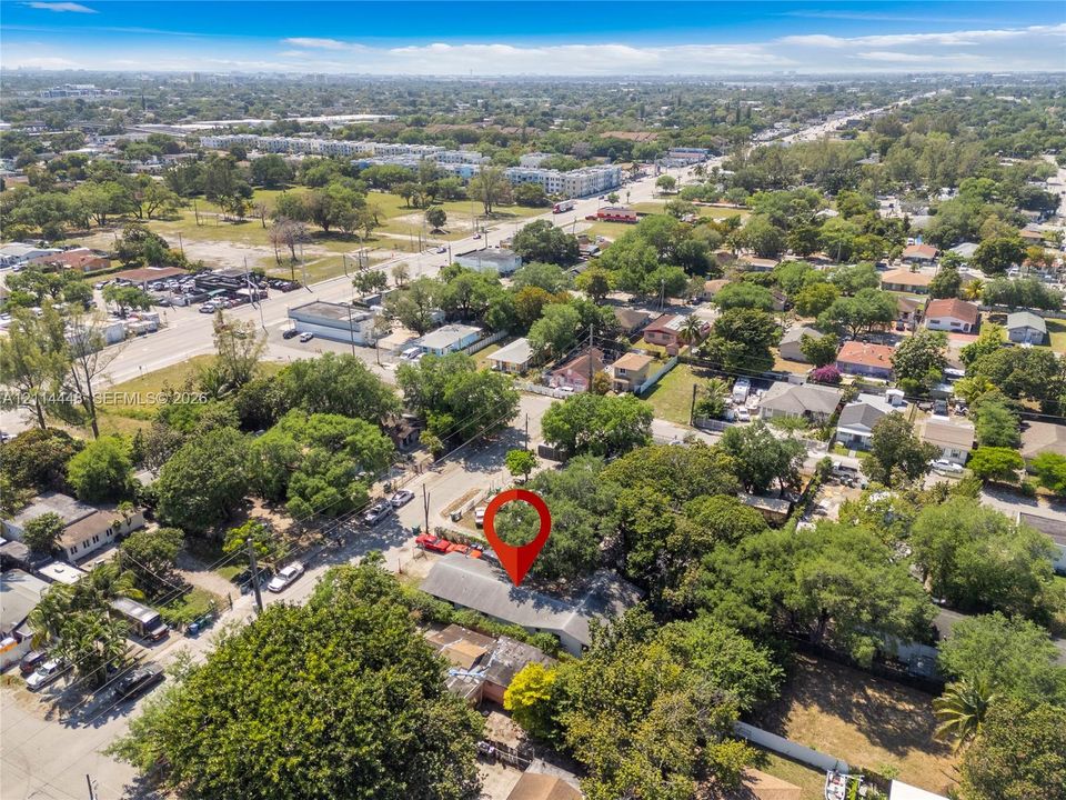 Aerial perspective featuring a lot with mature canopy trees, paved street access, and proximity to regional infrastructure