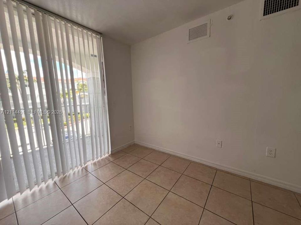 Interior space featuring large-format ceramic tile flooring and floor-to-ceiling vertical blinds covering the sliding glass door
