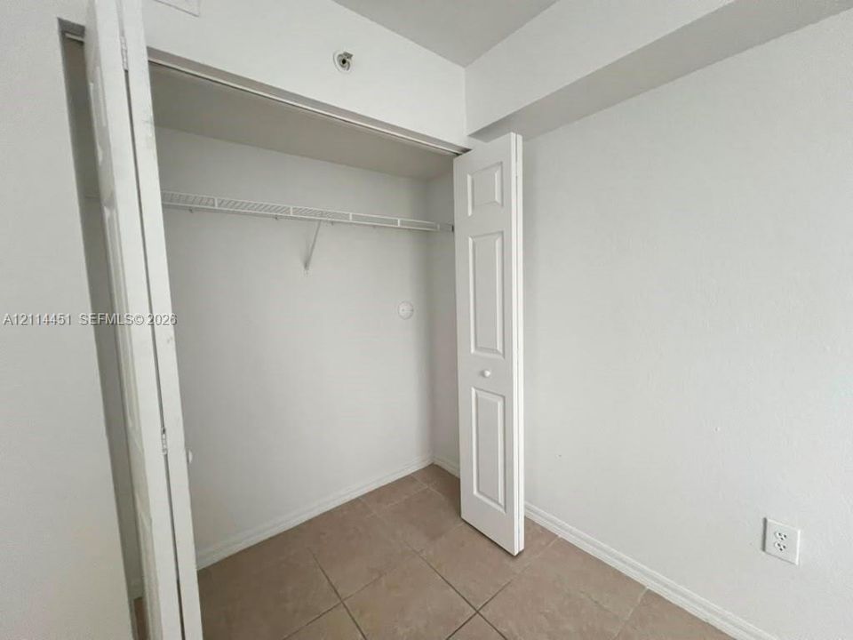 Closet featuring bi-fold panel doors, white interior walls, and neutral-tone tile flooring with integrated wire shelving