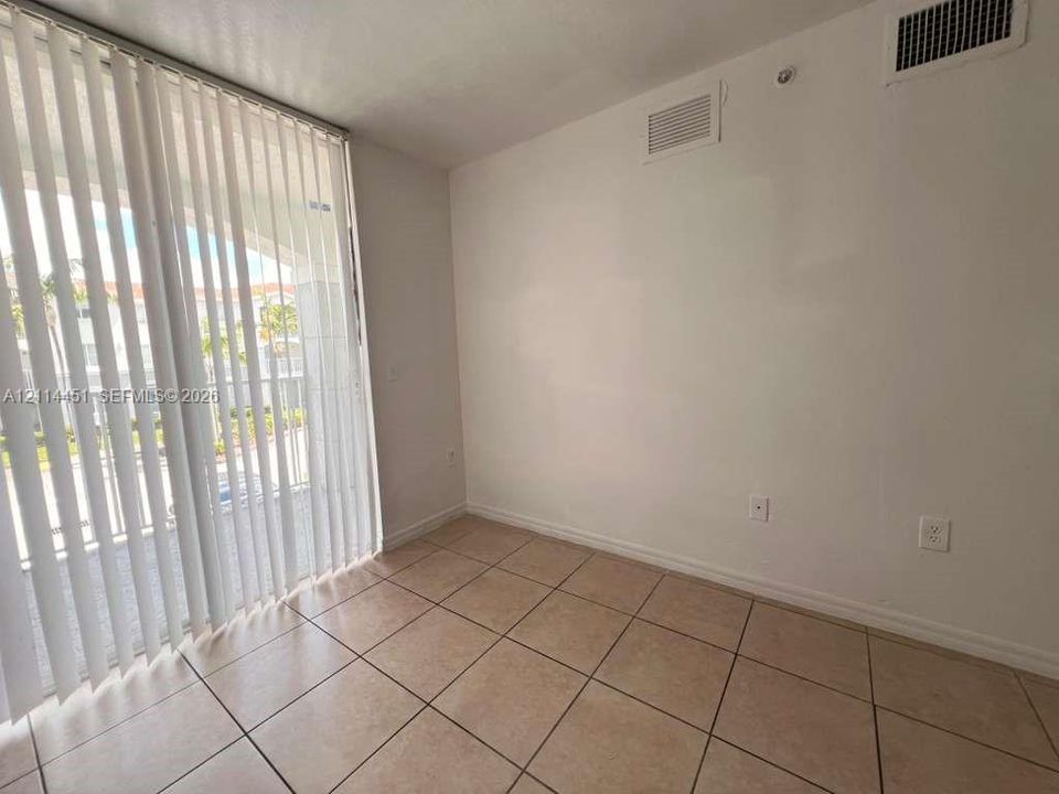 Neutral-toned ceramic tile flooring paired with full-height sliding glass doors featuring vertical blinds