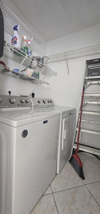 Laundry area featuring light-toned ceramic tile flooring and multi-tier wire shelving