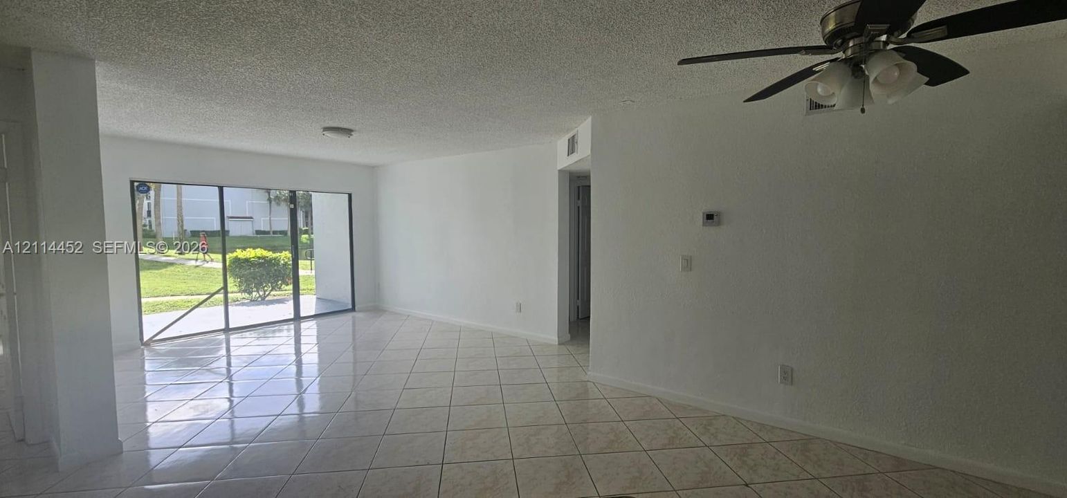 Large living space featuring tile flooring, ceiling fan with light fixture, and floor-to-ceiling sliding glass doors