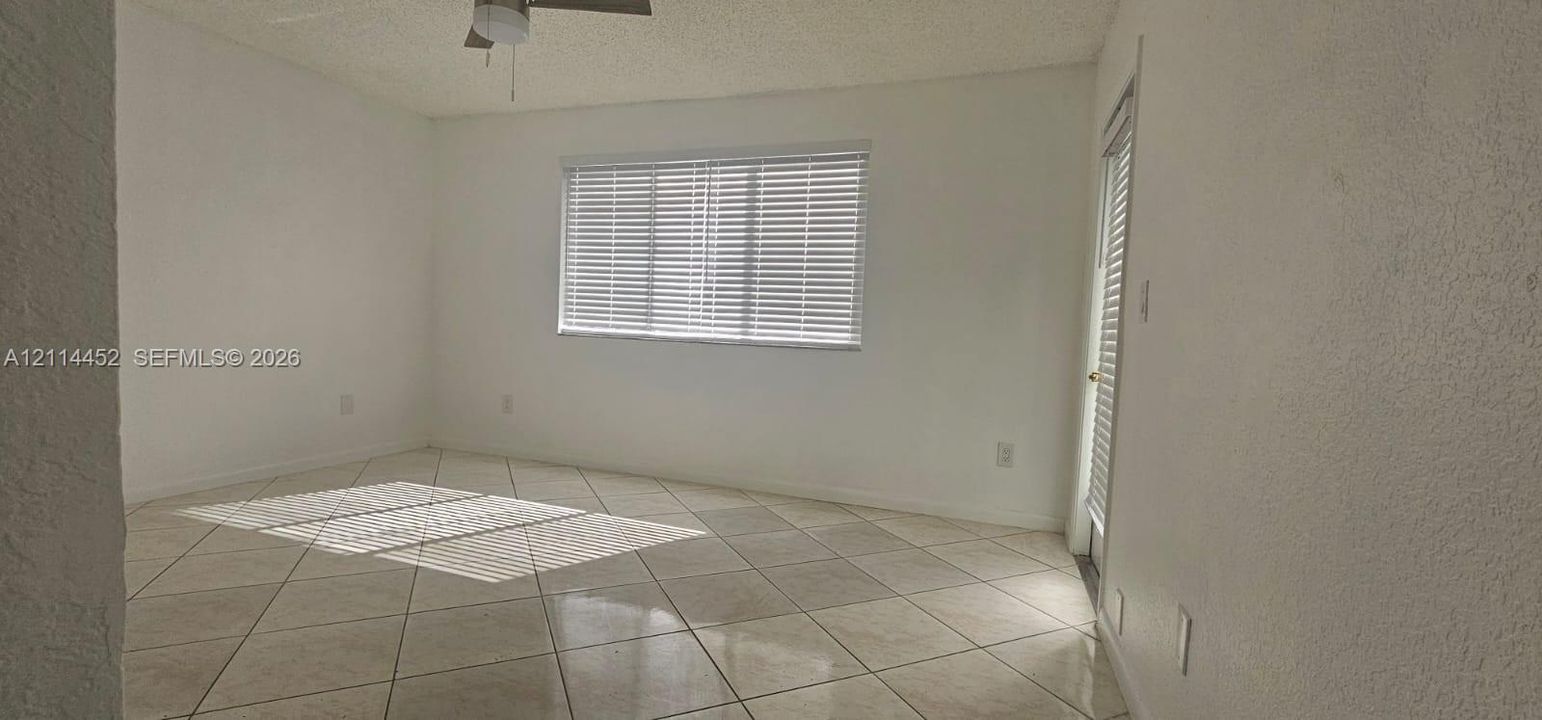 Room interior featuring large-format diagonal tile flooring, textured wall finish, and an integrated ceiling fan