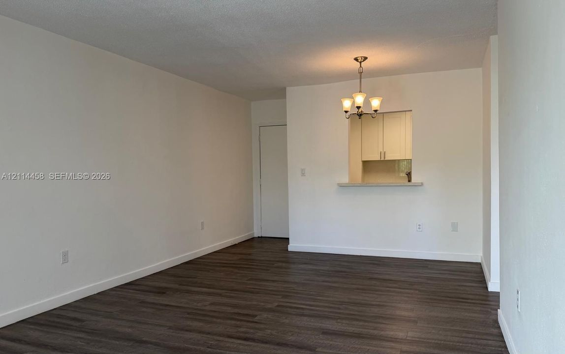 Open-concept interior featuring wood-finish flooring, a pass-through opening, built-in cabinetry, and a tiered chandelier