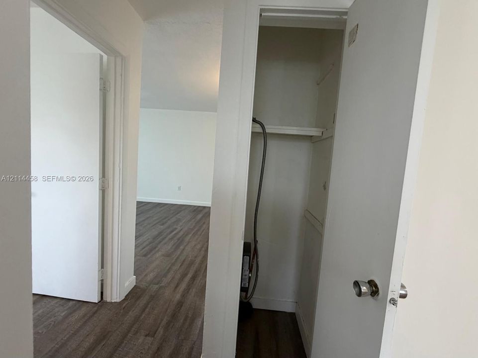 Wood-finish flooring throughout, interior closet with built-in shelving, and white panel doors with spherical hardware