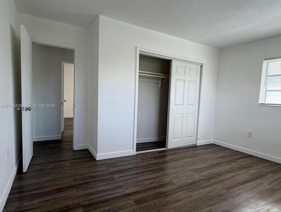 Interior space featuring wood-finish flooring, a closet with six-panel sliding doors, and a single-hung window
