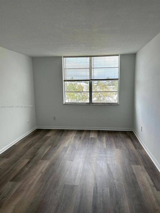 Neutral-toned interior space featuring wood-finish flooring and a multi-pane window