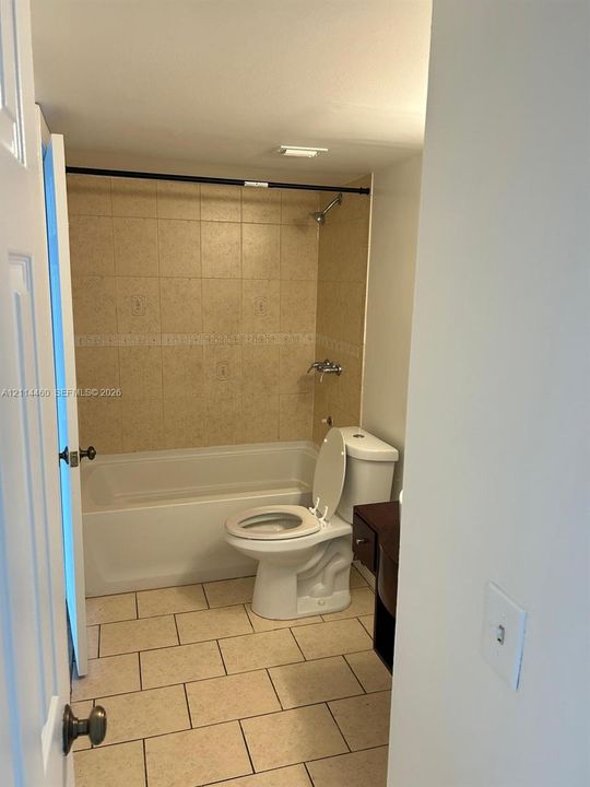 Full bathroom featuring a tub-shower combination with ceramic tile surround, ceramic tile flooring, and dark wood-finish cabinetry