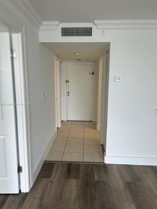 Entrance area featuring wood-finish flooring, ceramic tile tiling, and crown molding