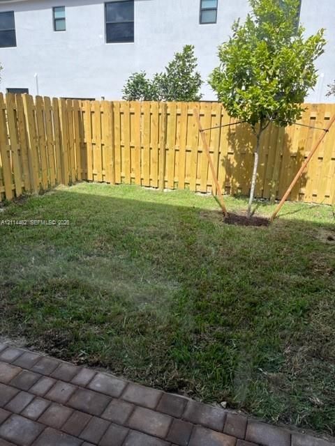 Private backyard featuring a paved patio, perimeter wood fencing, and a manicured lawn
